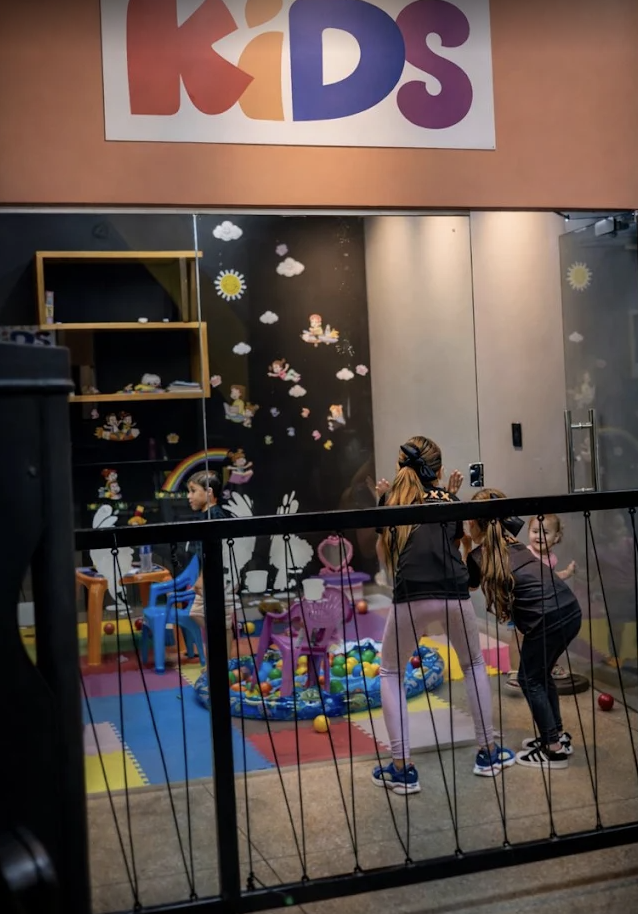 Espaço Kids da EVOXXe com brinquedos, mesas e crianças brincando